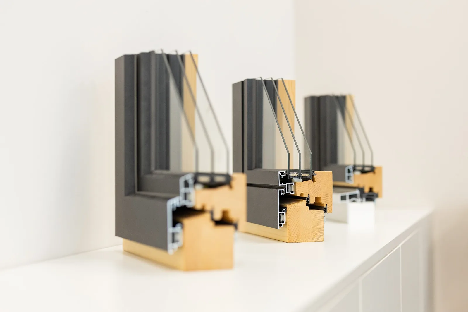 Drei aufgeschnittene Fensterprofile aus Holz und Aluminium